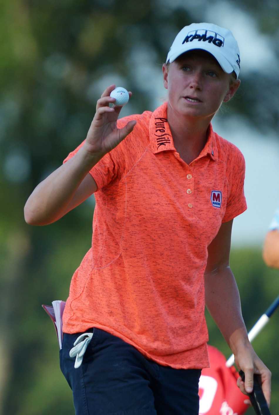 阳光洒在广阔的球道上，梁熙英走向下一个发球台，背影从容，象征着比赛仍在继续，挑战永不停歇