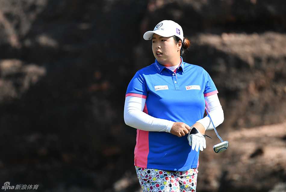 张哈娜在果岭上凝神观察小球滚动的路线，阳光勾勒出她专注的侧影。