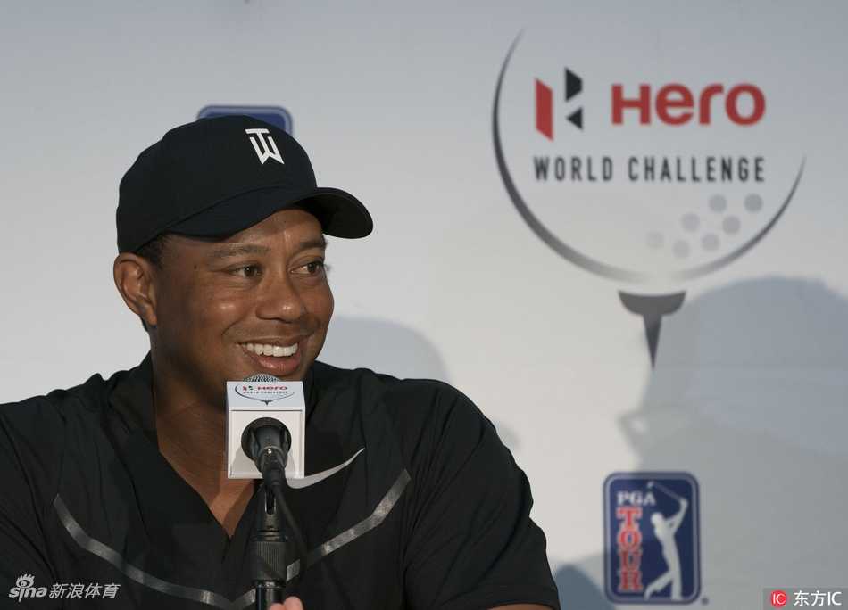 泰格·伍兹面带标志性微笑，自信地坐在发布会桌前，眼神锐利而坚定，仿佛已准备好迎接一切挑战。