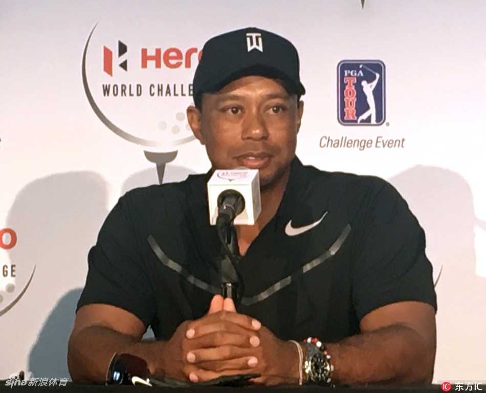 伍兹被记者们紧紧围在中心，他微微侧耳倾听提问，神情专注，周围是密密麻麻的录音设备与期待的面孔。