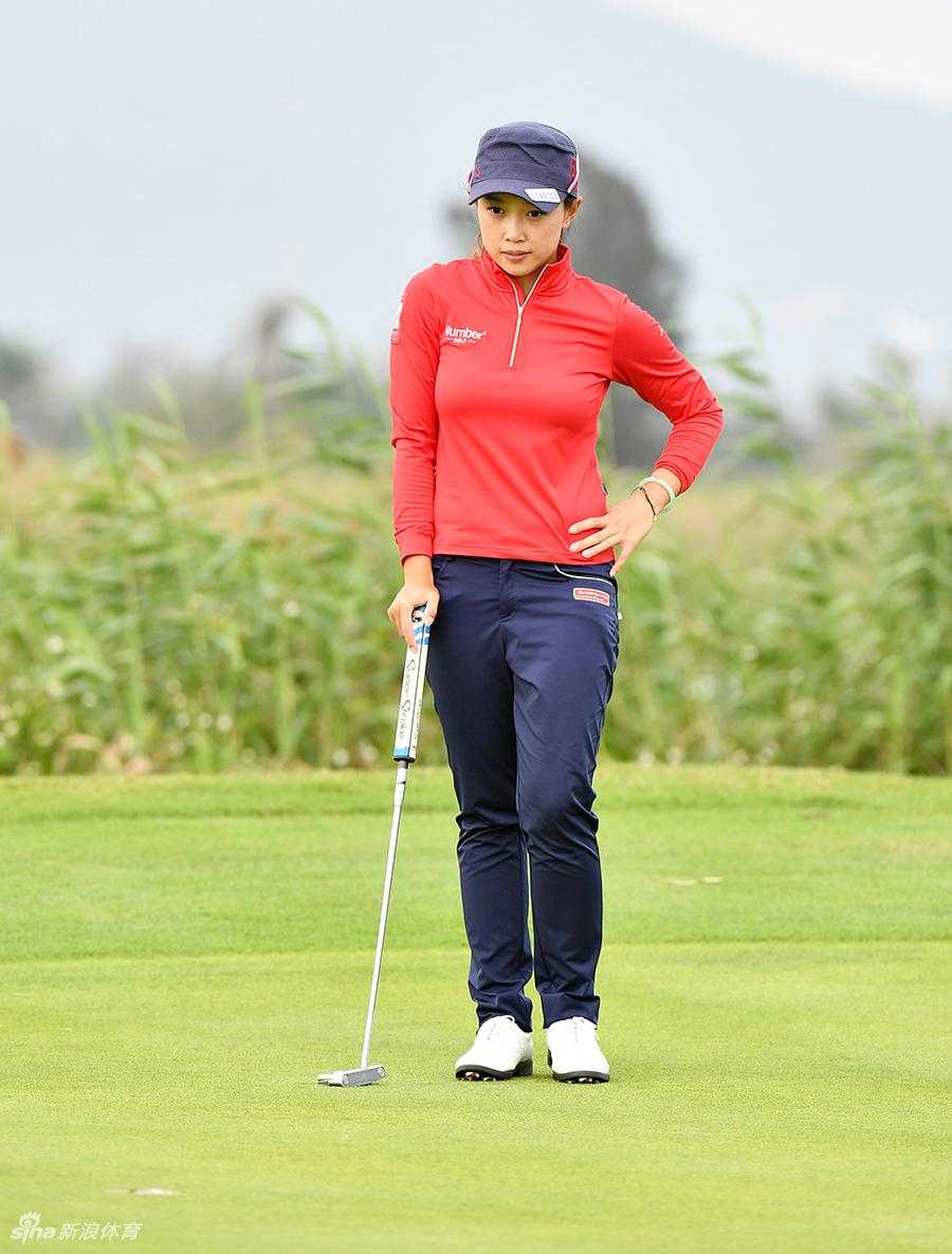 黎佳韵蹲在果岭边仔细观察草纹与坡度，为推杆做最后的测算