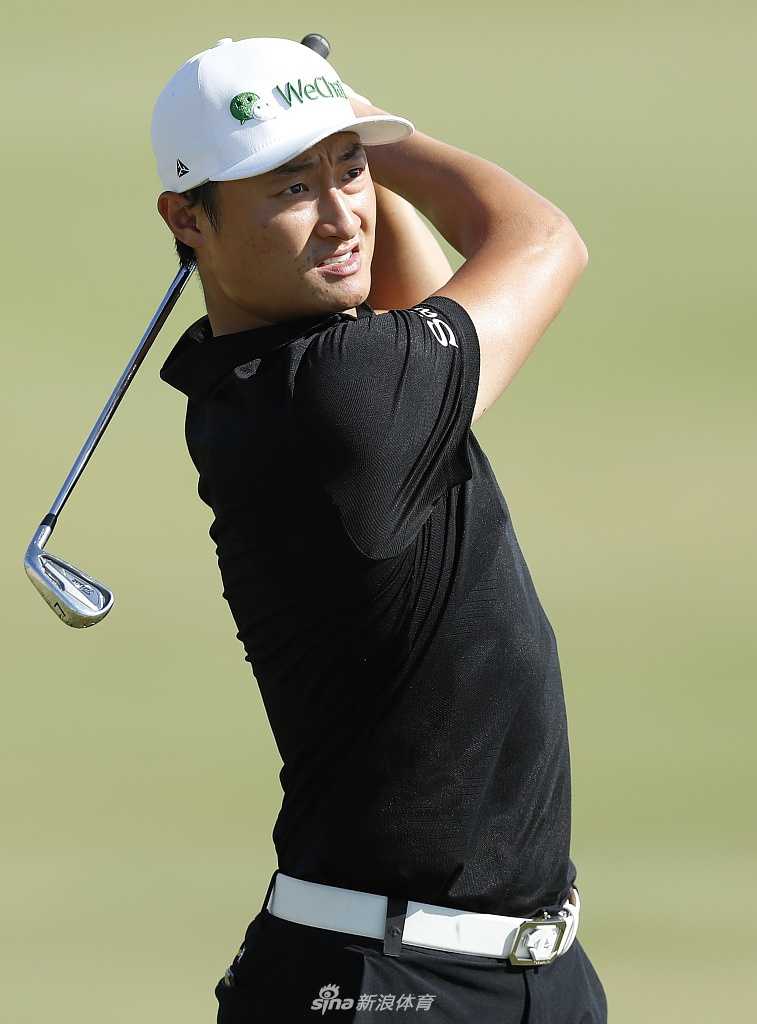 一名球童正在果岭上仔细擦拭高尔夫球，为球员的推杆做最后准备。