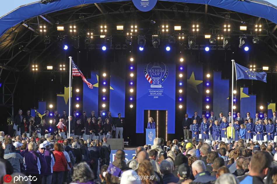 全景视角下的开幕式舞台，灯光如星河洒落，莎琳的身影在庞大却专注的观众席前显得充满力量，现场沉浸在一片音乐的海洋中。