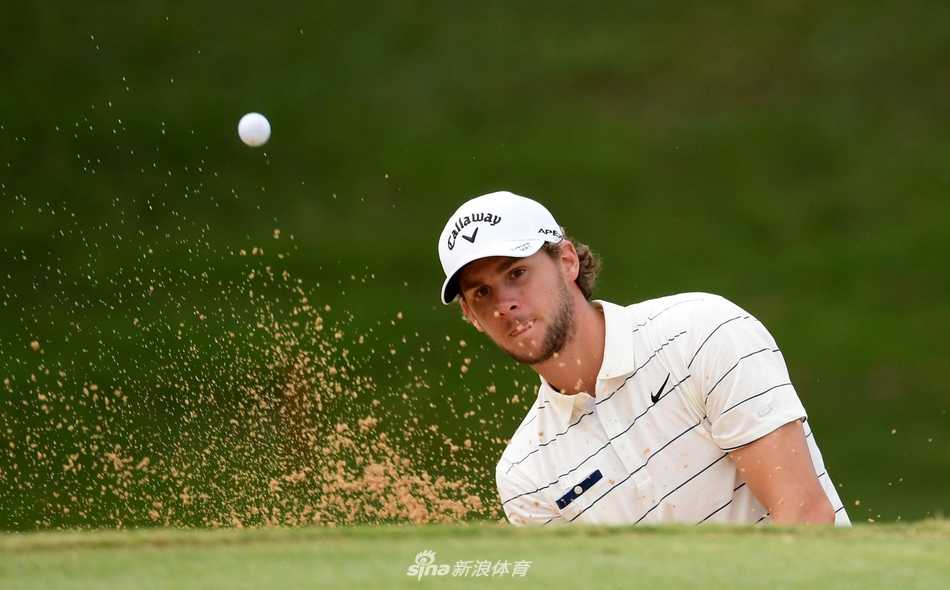 苏格兰高尔夫新星卡勒姆·希尔在毛里求斯传承赛球道上专注地进行击球准备，背景是热带独有的茂密丛林与晴朗天空。