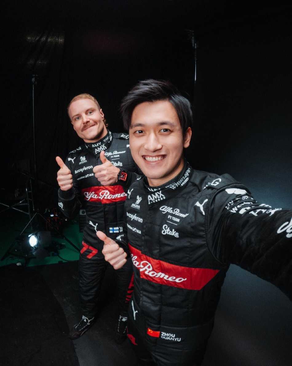 法拉利车队技师团队于维修站内进行紧张的最终调试，红色工作服在白色车库中格外醒目，众人目光聚焦，只为赛车驶上赛道前的完美一瞬。