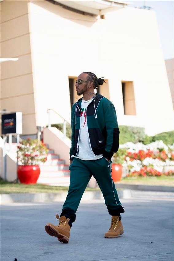 汉密尔顿佩戴头盔静坐于座舱之内，面罩反射着围场百态，深邃的目光中是对新征程的沉思与不变的对胜利的渴望。