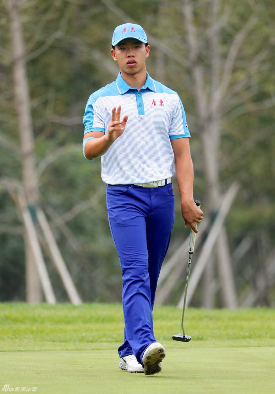 冠军选手关天朗在果岭上向观众挥手示意，笑容灿烂充满自信