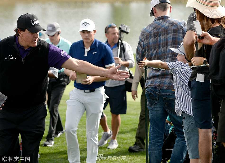 菲尔·米克尔森俯身与年轻小球迷亲切击掌互动，笑容灿烂充满亲和力