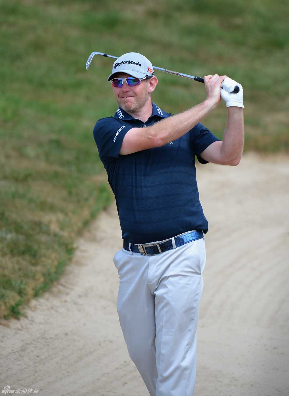 老将李·维斯特伍德在沙坑中救球后无奈摇头，沙尘微扬，背景是观众席模糊的身影