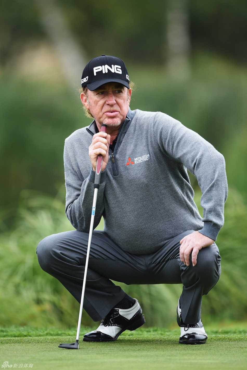 西班牙球员希梅尼兹在沙坑旁屈膝俯身，以独特的视角审视高尔夫球与果岭旗杆间的复杂关系与地形障碍。